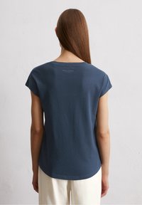 Merenhorison värinen puuvillapaita, jossa on pyöreä pääntie ja lyhyet hihat. Takana lähellä kaula-aukkoa on hillitty logoprintti. Silkkinen pinta.