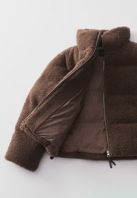 Braune Fleecejacke mit hohem Kragen, Reißverschluss vorne und glattem Innenfutter. Verfügt über eine weiche Textur und einen lässigen Schnitt.