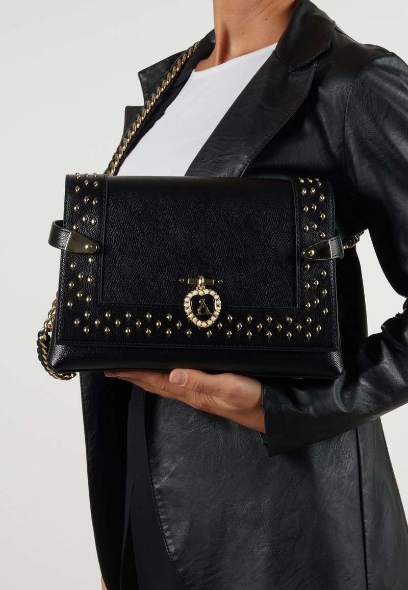Borsa a tracolla nera strutturata con accenti di borchie dorate, tracolla a catena e chiusura decorativa. Materiale testurizzato e finitura liscia.
