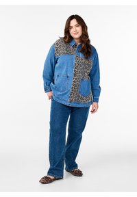 Džínová bunda s leopardím potiskem, modrý džínový materiál, dvě přední kapsy a zapínání na knoflíky. V kombinaci s modrými rozšířenými džíny a obuví s leopardím potiskem.