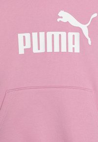 Sudadera rosa hecha de tejido suave, con un bolsillo frontal y un logo de PUMA en blanco con un gráfico de un puma saltando.