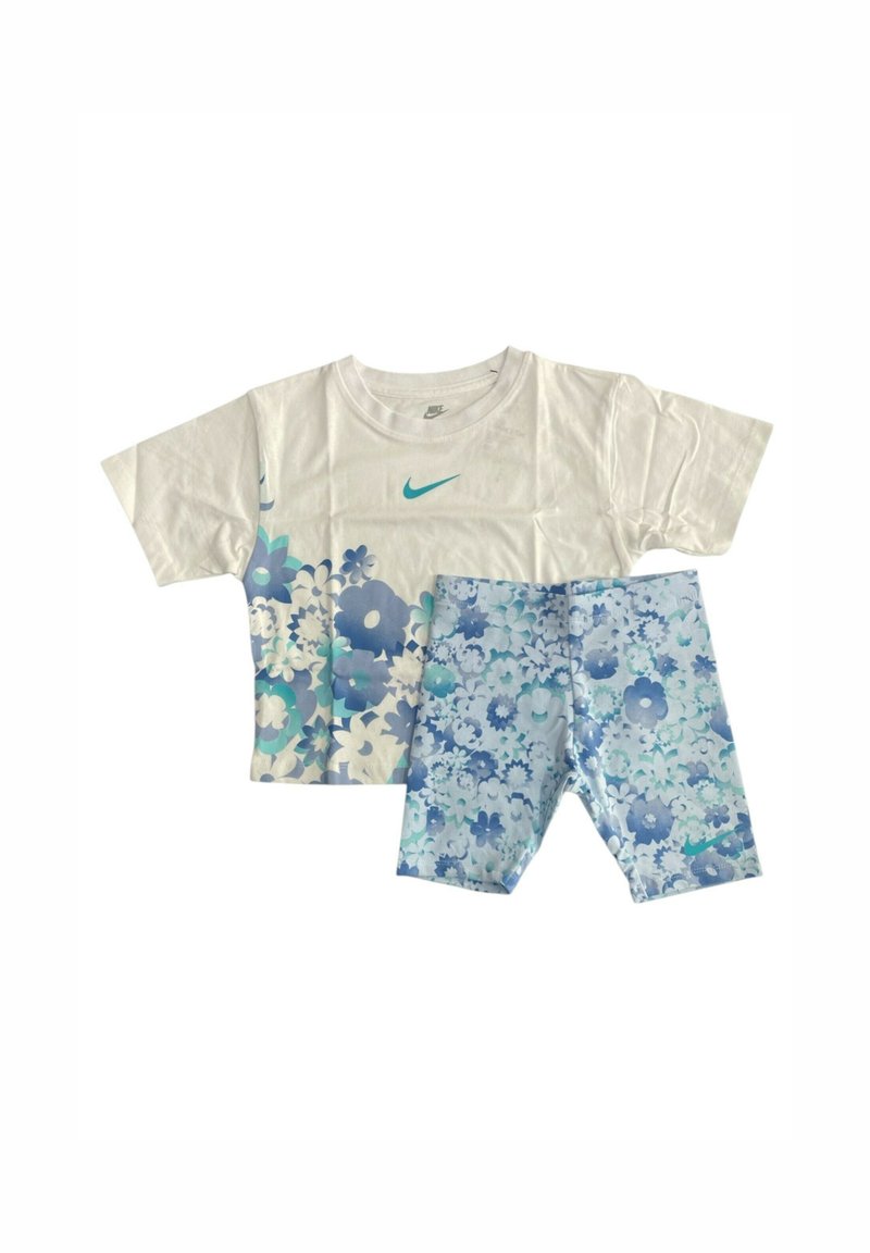 Camicetta corta bianca con motivo floreale blu e logo Nike turchese; pantaloni corti blu floreali coordinati con design simile.
