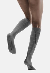 Calze a compressione grigie fino al ginocchio con righe orizzontali, texture liscia, punta rinforzata e decorazioni a motivo vicino al polpaccio e alla caviglia.