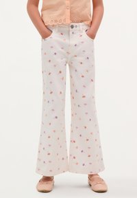 Witte uitlopende broek met een bloempatroon in oranje, paars en roze. Voorzien van voorzakken en een knoopsluiting. Zachte stofstructuur.