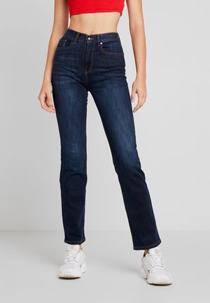Jeans de tiro alto en azul oscuro, fabricados en denim. Presentan un cierre de botón y cremallera, cinco bolsillos y detalles de costura sutiles.