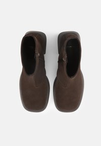 Brown suede ankle boots with a zip closure, square toes, and a low stacked heel. Smooth texture and minimalistic design.
