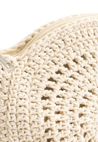 Krämfärgad, vävd virkade väska med en texturerad yta, som har dragkedjestängning och metalliska detaljer.