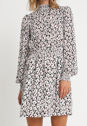 Bloemenjurk met een witte achtergrond, zwarte en rode bloemen, lange mouwen, gerimpelde taille en een losse pasvorm.