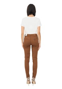 Brązowe slim-fit spodnie wykonane z elastycznej tkaniny, połączone z białą koszulą z krótkim rękawem; noszone z wzorzystymi szpilkami.