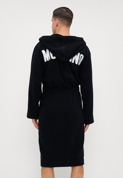 Accappatoio nero con cappuccio in morbido tessuto peluche, con cintura in vita. Sul retro presenta la scritta bianca "Moschino" nella parte superiore.