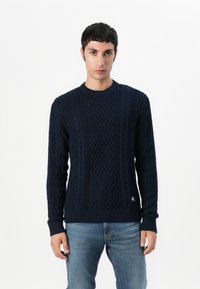 Donkerblauwe gebreide sweater met een gestructureerd kabelpatroon, een ronde halslijn en geribbelde manchetten en zoom. Gemaakt van een zachte, warme stof.