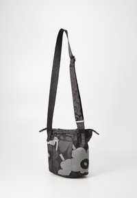 Black and gray shoulder bag with floral pattern, adjustable strap, and textured surface. Features a zipper closure and dual top handles.