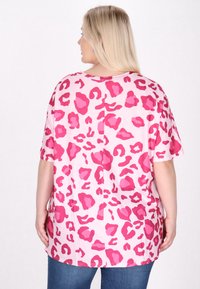 T-shirt med korte ærmer i lyserødt stof med leopardmønster i varierende nuancer af pink. Løs pasform med bølget kant og sideslidser.