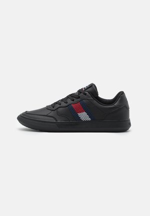 Sneakers neri in pelle con una texture liscia. Presentano un motivo a strisce diagonali colorate in rosso, bianco e blu sul lato.