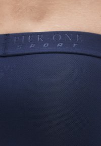 Μπλε αθλητική ζώνη μέσης με υφασμάτινη υφή, διαθέτει ανάγλυφη επωνυμία "PIER ONE", λεία επιφάνεια και στενή εφαρμογή.