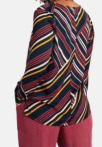 Chemise à manches longues avec un motif de rayures diagonales en marine, bordeaux, jaune et blanc. Tissu doux, ourlet arrondi et coupe décontractée.