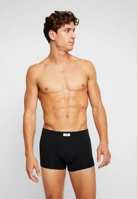 Svarta boxerkalsonger av bomull med en tajt passform, elastisk midjeresår och en etikett på framsidan. Slät textur och minimalistisk design.