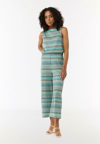 Top bez rękawów i szerokie spodnie w zestawie z falistym wzorem w odcieniach turkusu, kremu i brązu, wykonane z lekkiego materiału.