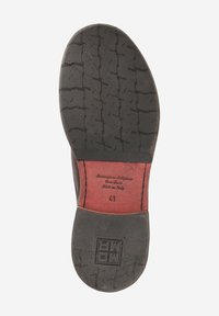 Semelle en caoutchouc noir avec un motif de grip texturé, doublure intérieure rouge et détails estampés. Tailles et logo de la marque visibles dans la zone du talon.