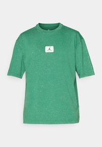 Grøn bomulds t-shirt med rund hals, korte ærmer og en falmet tekstur. Har en hvid firkantet lap med et grønt logo på forsiden.