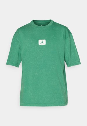 Grünes Baumwoll-T-Shirt mit Rundhalsausschnitt, kurzen Ärmeln und einem verwitterten Textur. Mit einem weißen quadratischen Patch mit grünem Logo auf der Vorderseite.