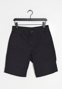 Mustat puuvillahousut suoralla leikkauksella, joissa on kaksi sivutaskua ja nappikiinnitys. Vyötärön lähellä on pieni yksityiskohta.