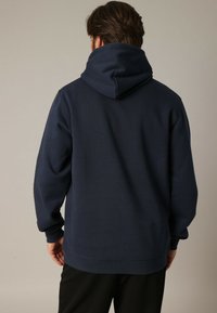 Marineblauwe hoodie met een grote achterkap, geribde boorden en zoom. Gemaakt van zacht, gemêleerd fabric met een relaxte pasvorm.