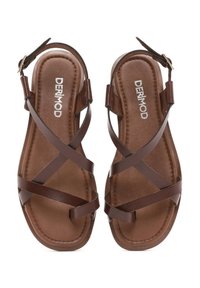 Sandalias de cuero marrón con correas cruzadas y suela plana. Cuentan con un cierre de hebilla y una plantilla suave y texturizada con logotipo en relieve.