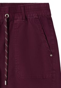 Shorts bordeaux à taille élastique avec cordon rayé, grande poche avant et détail de rivet métallique sur le côté droit.