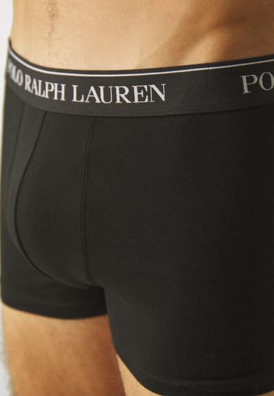 Melnas kokvilnas bokseru apakšbikses ar pieguļošu dizainu, kurām ir plata elastīga jostasvieta ar uzrakstu "POLO RALPH LAUREN" baltā krāsā.