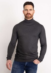 Pulover gri închis cu guler înalt, realizat dintr-un material tricotat moale, având mâneci lungi și o siluetă ajustată. Purtați-l cu blugi albaștri.