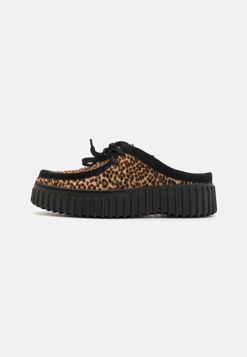 Leopard-patterned slip-on shoes with a black suede trim and a thick black rubber sole featuring vertical grooves for traction.