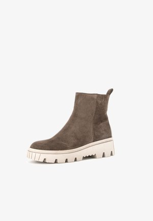 Braune Wildleder-Stiefelette mit einer dicken weißen Sohle, die ein strukturiertes Muster aufweist und hinten einen Zugschlaufe für einfachen Einstieg hat.