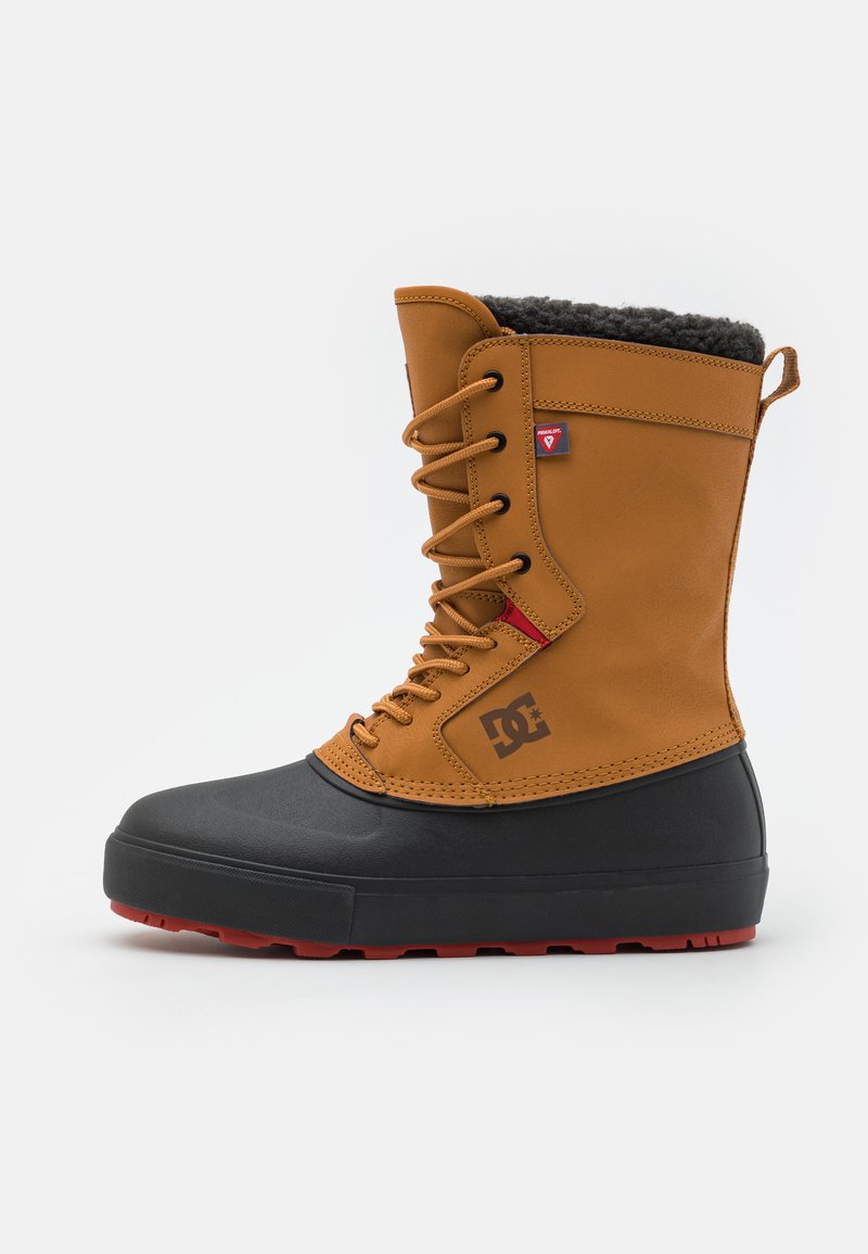 Bruine leren laars met zwarte rubberen zool, voorzien van rode accenten, grijze bontvoering en zwarte veters. Prominent DC-logo aan de zijkant.