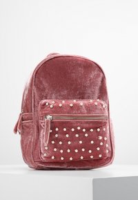 Rosa Samt-Rucksack mit abgerundetem oberen Teil, vorderer Reißverschlusstasche verziert mit weißen Perlen und plüschiger Textur. Verfügt über Seitentaschen und verstellbare Träger.