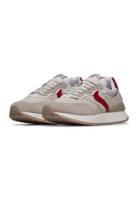 Sneaker in suede beige con accenti rossi, sovrapposizione testurizzata, lacci grigi e una suola intermedia bianca. Suola in gomma per trazione e durata.