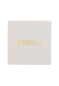 Vit fyrkantig yta med ordet "amor" skrivet i guld i gemener centrerat på den.