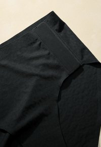 Black fabric shorts with a subtle hexagonal texture, featuring a smooth elastic waistband and clean stitching details.