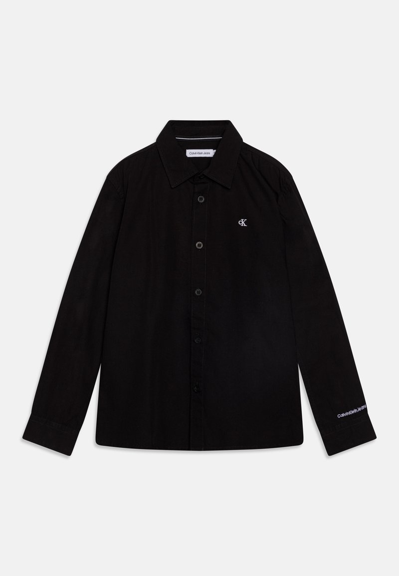 Svart skjorta med knappar, långa ärmar, spetstålig krage och CK-logga på bröstet. Har en slät textur och rät fåll.