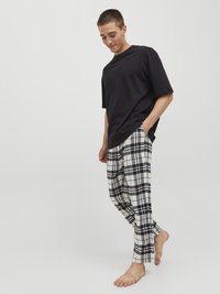 Svart t-shirt med kort ärm som kombineras med rutiga pyjamasbyxor i vitt och svart. Byxorna har synliga sidofickor och en avslappnad passform.