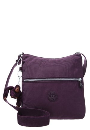 Sac bandoulière violet avec poche zippée à l'avant et porte-clés peluche singe attaché à la sangle réglable.