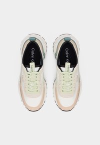 Ζευγάρι λευκά και παστέλ μπεζ sneakers Calvin Klein με ανοιχτοπράσινα κορδόνια, σε άποψη από πάνω σε λευκό φόντο.