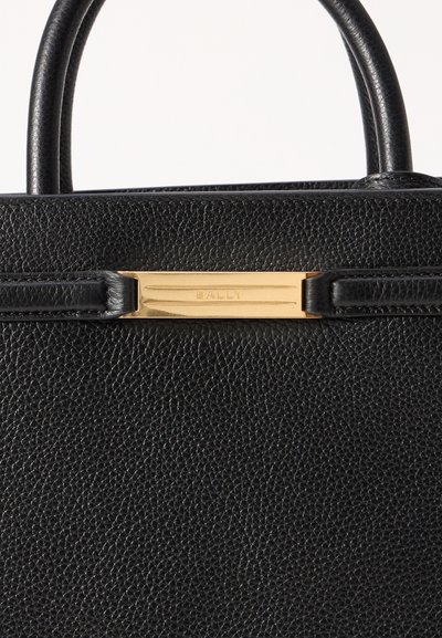 Mustapahkainen nahkalaukku, jossa on teksturoitu pinta, varustettuna lyhyillä kahvoilla ja kultaisilla metalliosilla, joissa on brändin nimi "BALLY."