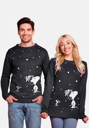 Knitted black sweaters featuring a white Snoopy design with snowflakes. The male and female models wear relaxed-fit styles.