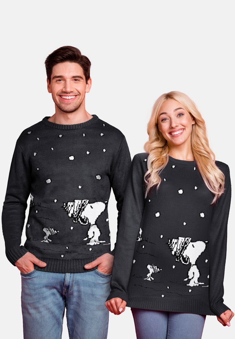Knitted black sweaters featuring a white Snoopy design with snowflakes. The male and female models wear relaxed-fit styles.