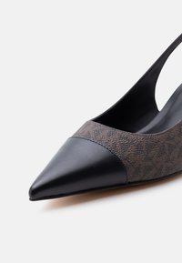 Γυναικείο πέδιλο με μυτερή μύτη, μαύρη δερμάτινη προστασία στη μύτη και επάνω μέρος από υφή σκούρου καφέ υφάσματος.