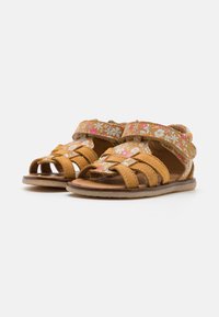 Tan sandals met bloemenpatroonbandjes, open teenontwerp, verstelbare klittenbandsluitingen en gevoerde zolen. Platte rubberen zolen.