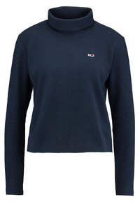 Maglione a collo alto blu navy con maniche lunghe, realizzato in materiale morbido. Presenta una piccola etichetta con logo nell'area del petto sinistro.