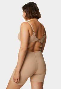Set di reggiseno beige senza cuciture e pantaloni corti a vita alta, con spalline regolabili, una texture liscia e hardware minimo.