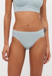 Svetlomodrý čipkovaný bralet a nohavičky, s ozdobným okrajom a geometrickým vzorom, vyrobené z jemného priesvitného materiálu.